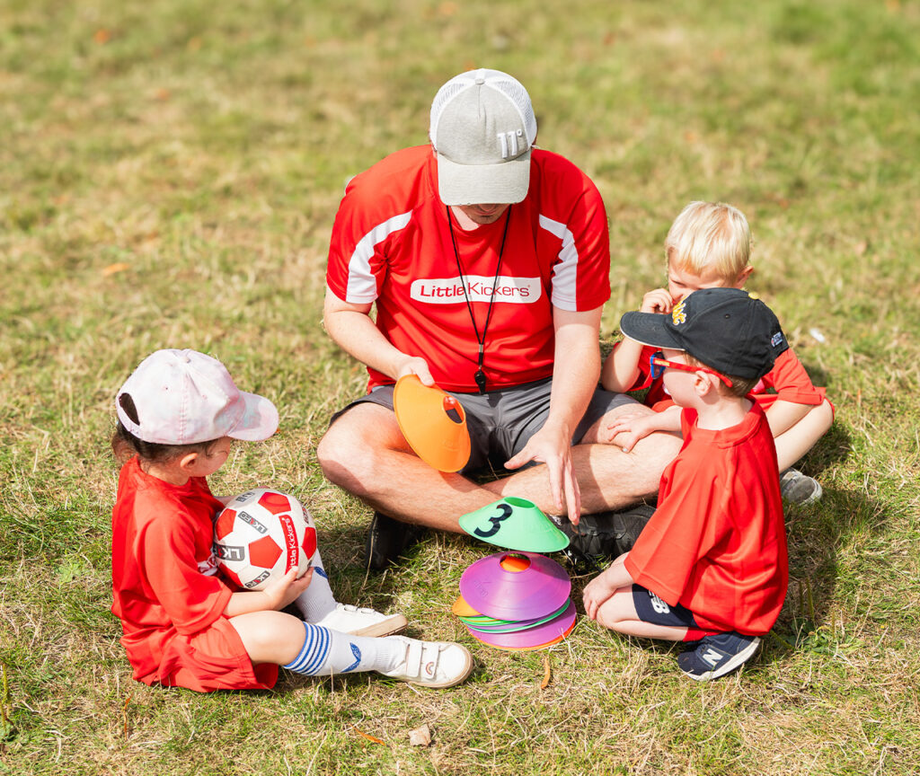 a group of kids sitting on grass with a coach