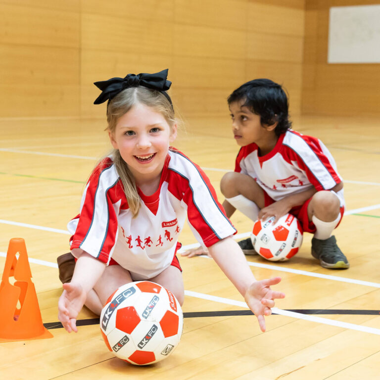 a group of kids sitting on the floor with footballs
